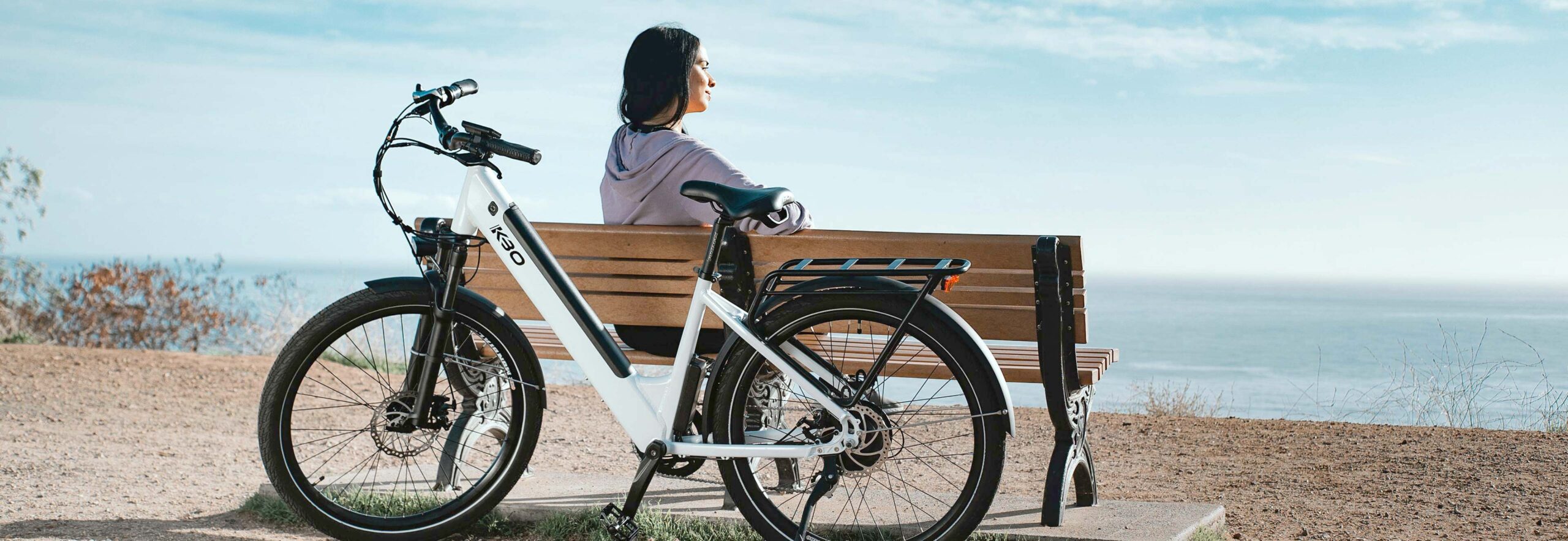 Woman Sitting on Bench with Electric Bike Behind Her